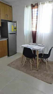 a kitchen with a table and two chairs and a refrigerator at 4 vecinos in Santiago de los Caballeros