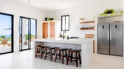 a kitchen with a large white counter and bar with stools at Private Villa-Infinity Pool-26 guests capacity-14 King Size Beds-8 bedrooms-8 and half baths in Cabrera