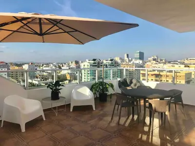 a balcony with a table and chairs and an umbrella at Eclectic 3 levels and 5 bedrooms penthouse in Santo Domingo