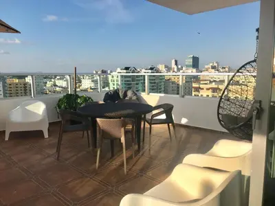 a balcony with a table and chairs and a view of a city at 3 levels and 5 bedrooms penthouse with a great view in Santo Domingo