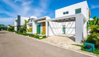a white house with a driveway at Sunbreeze Villa in Oceanfront Sosua Ocean Village in Sosúa