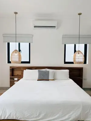 a bedroom with a large white bed with two pendant lights at Boho Villa in Oceanfront Comm Sosua Ocean Village in Sosúa