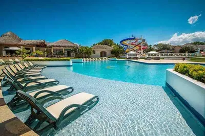 a row of chaise lounge chairs in a swimming pool at a resort at Villa Solana in Oceanfront Com Sosua Ocean Village in Sosúa