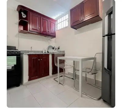 a kitchen with wooden cabinets and a table and chairs at Hermoso apartamento en piantini Santo Domingo RD in La Julia