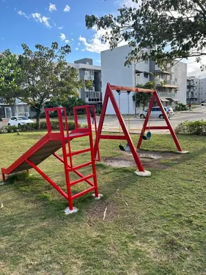two red playground equipment sitting in the grass at Cozy 3br apartment near to airport & beaches in La Cana