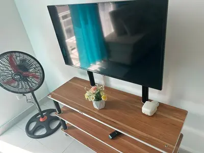 a flat screen tv on a wooden stand with a fan at Cozy 3br apartment near to airport & beaches in La Cana