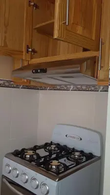 a stove top oven in a kitchen with wooden cabinets at Apartamentos Nuevo Amanecer in Río San Juan