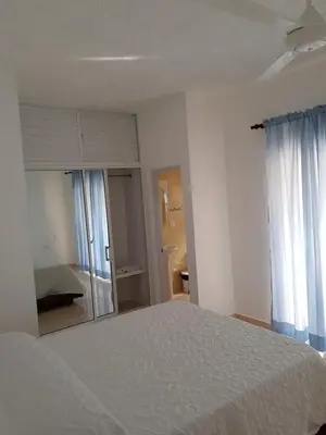 a bedroom with a white bed and a bathroom at Apartamentos Nuevo Amanecer in Río San Juan