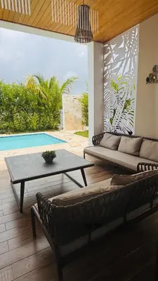 a living room with a couch and a table and a pool at Villa YOSYMART Poolside Retreat private WIFI Luxury BBQ side in Punta Cana