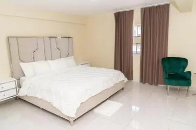 a bedroom with a large bed and a green chair at La Isla Royal - Abismo Celeste in Miches