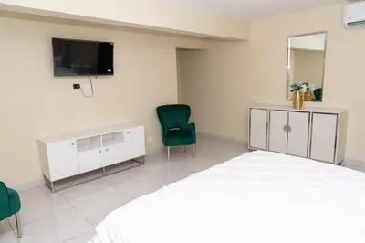 a bedroom with a bed and a tv and two chairs at La Isla Royal - Abismo Celeste in Miches