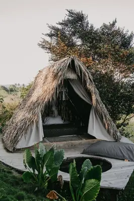 a bed with a grass roofed tent in a field at OYA New Earth Luxury Romantic Glamping with Private Outdoor Bath in Jamao al Norte