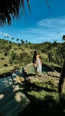 a woman in a white dress standing next to a pool at OYA New Earth Luxury Romantic Glamping with Private Outdoor Bath in Jamao al Norte