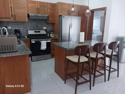 a kitchen with a island with chairs and a refrigerator at Villa Serene Breeze Private Pool Sosua Ocean Village in Sosúa
