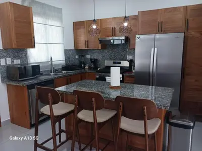 a kitchen with a counter with chairs and a refrigerator at Villa Serene Breeze Private Pool Sosua Ocean Village in Sosúa