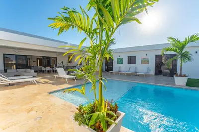 a pool with a palm tree next to a house at Kcasama Castle Villa 1108 in Sosúa