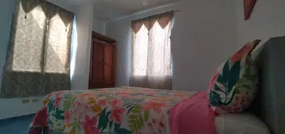 a bedroom with a bed and two windows at Apartamentos grigri in Río San Juan