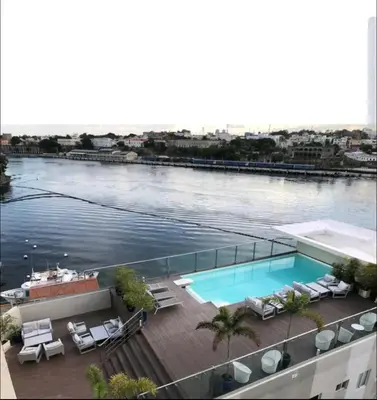 a swimming pool with chairs and a body of water at Vista Colonial, en el Residencial Riviera Colonial in Calero