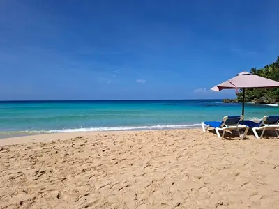 two chairs and an umbrella on a beach at Hermosa villa familiar cucu's home beach in Río San Juan