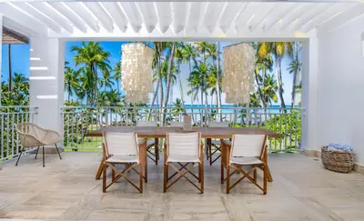 a dining room with a table and chairs and palm trees at Playa Bonita Modern Beachfront Penthouse - 3BR in Las Terrenas