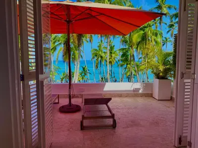 a red umbrella in a room with a view of the ocean at Playa Bonita Modern Beachfront Penthouse - 3BR in Las Terrenas