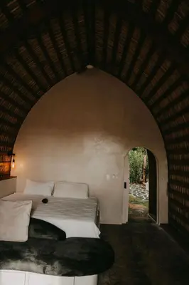 a bedroom with a large bed in an archway at OYA New Earth Private Jungle Cabin with Individual Campfire in Jamao al Norte