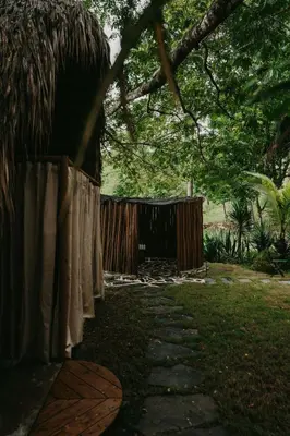a fence with white curtains in a yard at OYA New Earth Private Jungle Cabin with Individual Campfire in Jamao al Norte