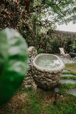 a stone bath tub sitting in the grass at OYA New Earth Private Jungle Cabin with Individual Campfire in Jamao al Norte