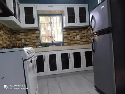 a kitchen with white cabinets and a stainless steel refrigerator at Recidencia Don Carlos