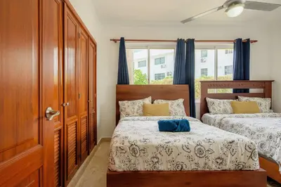 a bedroom with two beds with blue curtains at Playa Privada | Terraza & Piscina • WiFi Rápido in Punta Cana