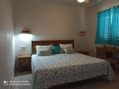 a bedroom with a large bed with blue curtains at Beachfront apartment in Las Terrenas