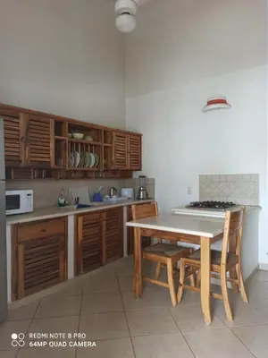 a kitchen with wooden cabinets and a table with chairs at Beachfront apartment in Las Terrenas