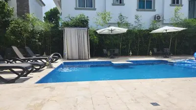 a swimming pool with chairs and umbrellas next to a building at Casa club by mama nelsy in Santa Cruz de El Seibo