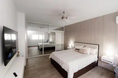 a bedroom with a large white bed and a mirror at TRACADERO Ocean Pearl Suite in La Laguna
