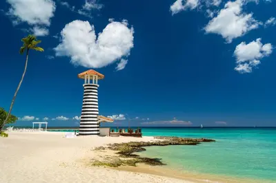a lighthouse on a beach with a palm tree and the ocean at TRACADERO Ocean Pearl Suite in La Laguna