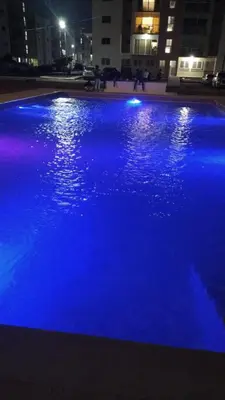 a swimming pool with blue lights in a city at night at Seaside Elegance in Baní