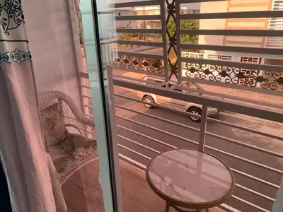 a balcony with a chair and a glass table at Seaside Elegance in Baní