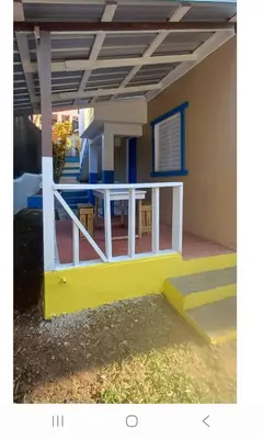 a house with a yellow and white porch at Nido de amor in Jarabacoa