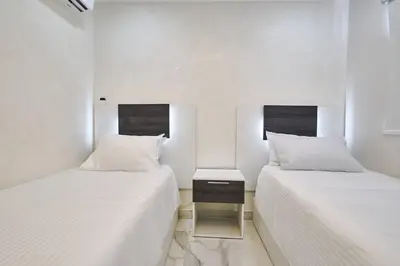 two beds in a room with white walls at Lovely 3 Bedroom Apartment, Pool,Gym,2parking S in Santo Domingo