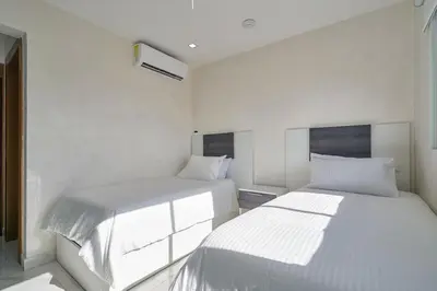 two beds in a room with white walls at Lovely 3 Bedroom Apartment, Pool,Gym,2parking S in Santo Domingo