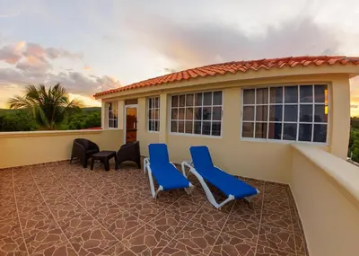 a patio with blue chairs and a house at Hotel la Saladilla Beach Club in Santa Cruz de Barahona