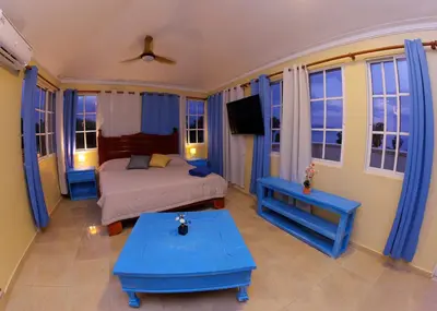 a bedroom with a bed with blue furniture and windows at Hotel la Saladilla Beach Club in Santa Cruz de Barahona