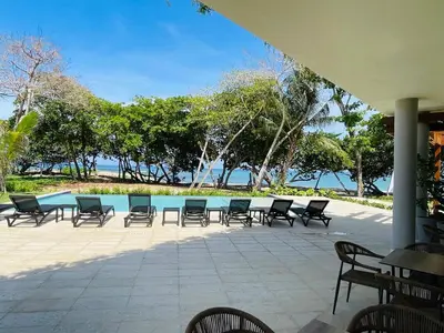 a patio with chairs and a table and a pool at Marien Residences 305 Deluxe High Floor Condo in Puerto Plata