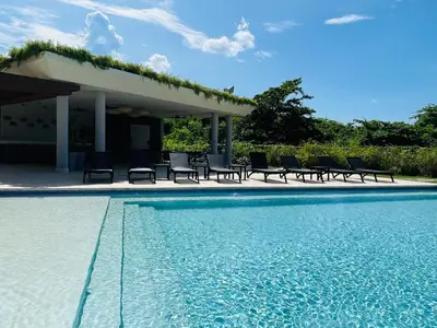 a swimming pool with chairs and a pavilion at Marien Residences 305 Deluxe High Floor Condo in Puerto Plata