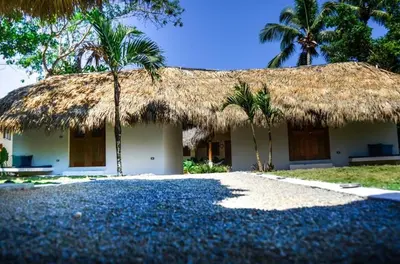 a house with a straw roof and palm trees at Nomadas 5 bdrs villa with private pool 2nd line to beach in Las Terrenas