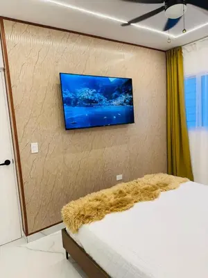 a bedroom with a bed with a flat screen tv on the wall at Modern Apartment in Bayahibe in Bayahibe