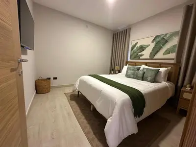 a bedroom with a large bed and a flat screen tv at Garden Breeze Ghibli-Pool View in La Laguna