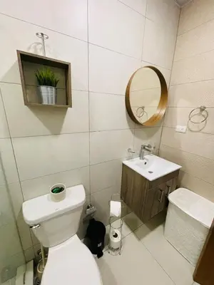 a bathroom with a toilet and a sink and a mirror at Oasis Residences, Modern 3BR Apartment with Pool in San Felipe de Puerto Plata