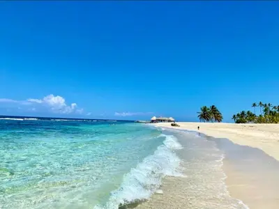 a beach with turquoise water and palm trees at Modern 2BR Condo Near the Beach Juan Dolio in Villas del Mar