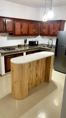 a kitchen with a wooden island in the middle at Modern 2BR Condo Near the Beach Juan Dolio in Villas del Mar
